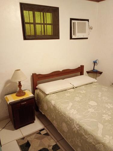 a bedroom with a bed and a table with a lamp at Pousada Arboretum in Penedo