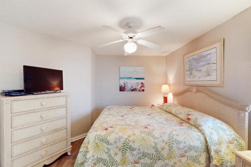 a bedroom with a bed and a flat screen tv at Four Winds 701 in Romar Beach