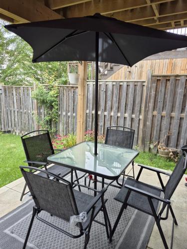 a table and chairs with an umbrella on a patio at Nimo Homestay , New Entire Studio Apartment Guelph in Guelph