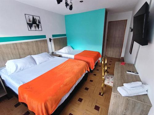 a bedroom with two beds and a flat screen tv at HOTEL CASA VECCHIA San Antonio in Cali