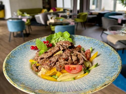 a plate of food with meat and vegetables in a restaurant at Malinowski Leśny in Gliwice