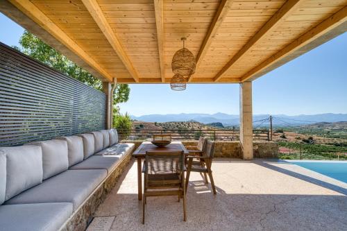 un patio con sofá, mesa y sillas en Elena's Sunset Villa, en Piryiótika