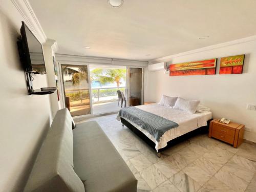 a bedroom with a bed and a tv and a balcony at Aptos Sunrise Beach in San Andrés
