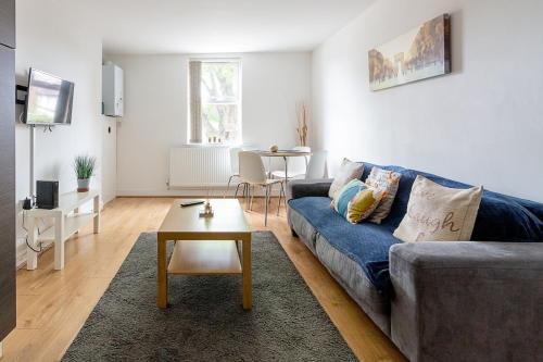 a living room with a blue couch and a table at 2 Bedroom Large First Floor Apartment with FREE Parking in Loughborough