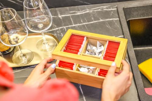 a person holding a wooden box on a table with wine glasses at Villa Cocosinella Belgrade in Surčin