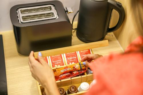 a woman is reaching for food in a toaster at Villa Cocosinella Belgrade in Surčin