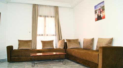 a brown couch in a living room with a window at Hotel Nouzha in Fès