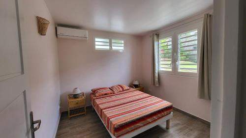a small bedroom with a bed and a window at Terrasses ouvertes sur la mer in Schœlcher