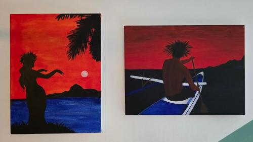 two paintings on a wall with a man in a boat at La Maison de l'Artiste in Hauru