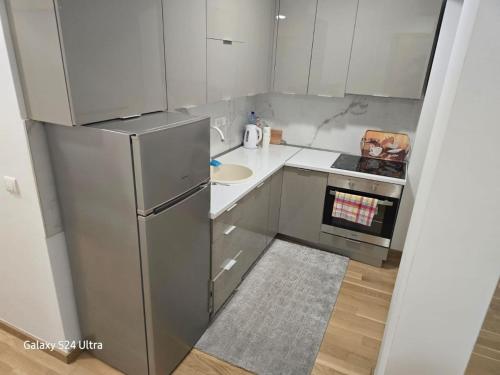 a small kitchen with a refrigerator and a sink at AiM apartman Bjelasnica in Bjelašnica