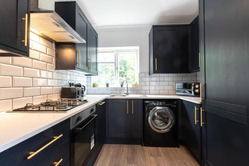 a kitchen with black cabinets and a washing machine at KGV Stays - Serenity House 3 bedroom near to the hospital with parking in Southampton