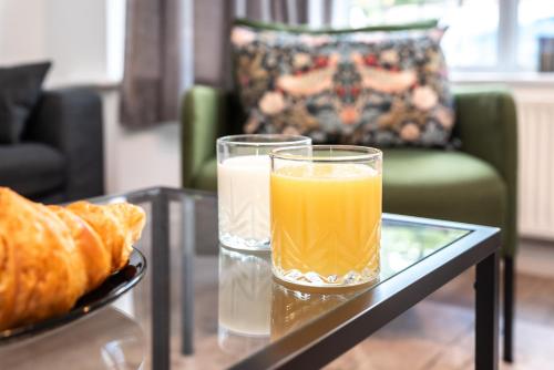 two glasses of orange juice and a plate of bread on a table at KGV Stays - Serenity House 3 bedroom near to the hospital with parking in Southampton