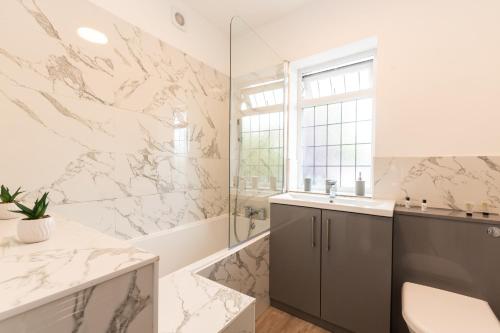ein Badezimmer mit Marmorwänden, einem Waschbecken und einer Dusche in der Unterkunft KGV Stays - Serenity House 3 bedroom near to the hospital with parking in Southampton