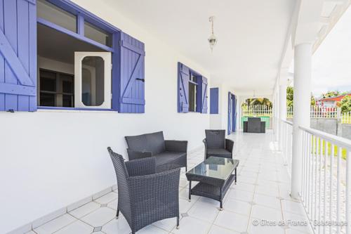 a living room with chairs and a table on a balcony at Villa B&M in Les Abymes