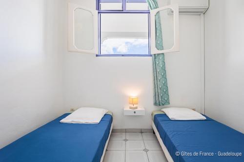 a small room with two beds and a window at Villa B&M in Les Abymes