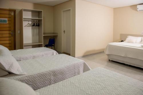 a bedroom with two beds and a blue chair at Hotel Tropical Garden in Primavera do Leste