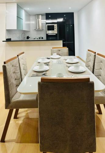 a dining room table with chairs and a kitchen at Levy-Cardoso Apartment in Praia