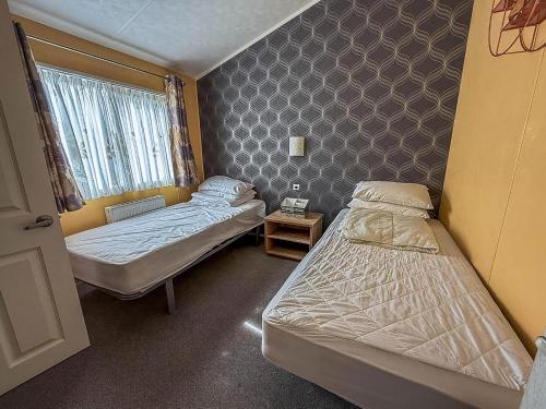 a small room with two beds and a window at Stunning Lodge With Decking At Oaklands Holiday Park In Essex Ref 39017Rw in Clacton-on-Sea