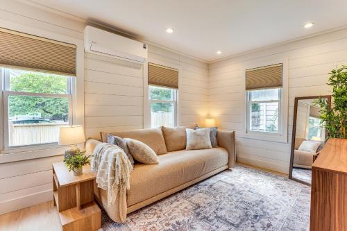 a living room with a couch and windows at 3 Mi to Michigan State Tiny Home with Deck! in Lansing