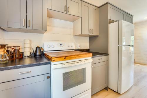 a kitchen with white cabinets and a white refrigerator at 3 Mi to Michigan State Tiny Home with Deck! in Lansing