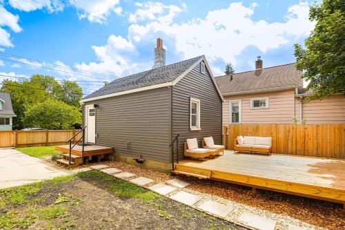 a wooden deck with two chairs and a house at 3 Mi to Michigan State Tiny Home with Deck! in Lansing