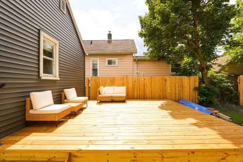 a backyard with two chairs and a wooden deck at 3 Mi to Michigan State Tiny Home with Deck! in Lansing