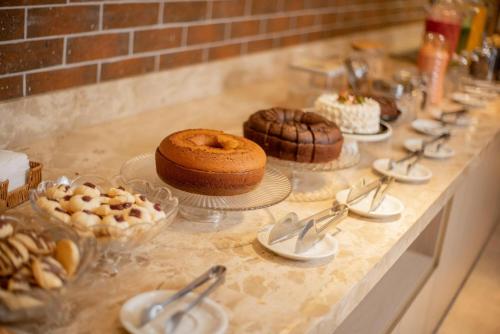 a buffet with cakes and other desserts on a counter at Hotel Tropical Garden in Primavera do Leste