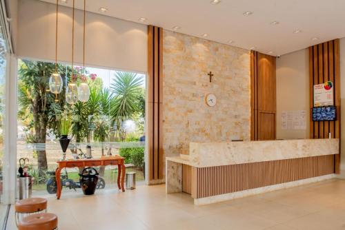 a lobby with a table and a large window at Hotel Tropical Garden in Primavera do Leste