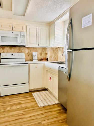 a kitchen with white cabinets and a refrigerator at The Seahorse, a 2bed beach paradise in Fernandina Beach, swimming pool! in Fernandina Beach