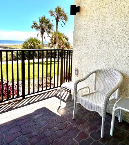 two white chairs sitting on a patio with a fence at The Seahorse, a 2bed beach paradise in Fernandina Beach, swimming pool! in Fernandina Beach