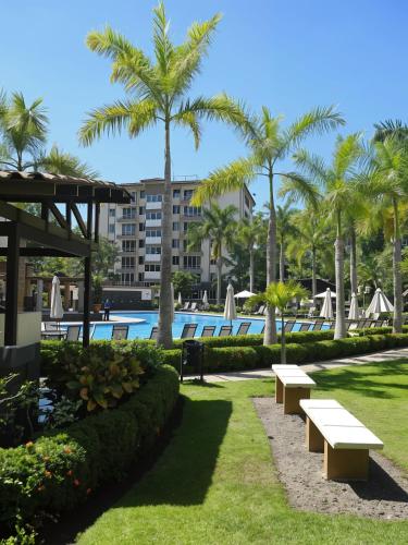 a park with benches and palm trees near a swimming pool at Costa Linda Amazing 1-03! in Jacó