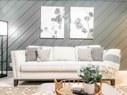 a living room with a white couch and three paintings at Serene Private Two Bedroom Townhouse in East TLH in Perkins