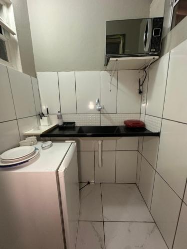 a small white kitchen with a sink and a microwave at Suites por do Sol in Búzios