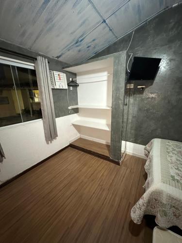 a small room with a bed and a window at Suites por do Sol in Búzios