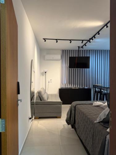 a bedroom with a bed and a television on a wall at Studio lnhô Tim in Brumadinho