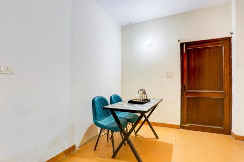 新德里Super Hotel O KC的一张桌子和两把椅子,放在一个有门的房间