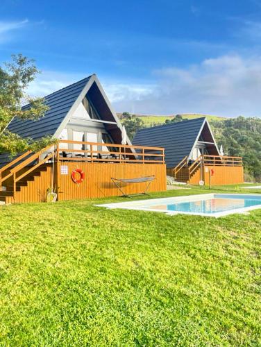 a home with a swimming pool and a house at Chalés Luna In Rio Chalé Rio in Ponte da Barca