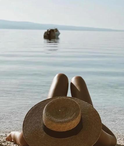 a woman laying on the beach with a straw hat at Beach Side Holiday in Omiš