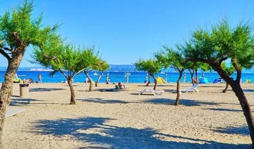 a beach with trees and people on the beach at Beach Side Holiday in Omiš