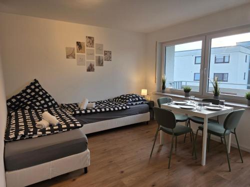 two beds and a table in a room with a table and chairs at Gemütliches Apartment mit Balkon - Hans NU2 in Neu Ulm