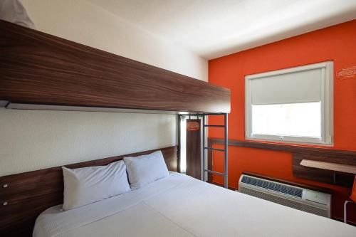 Un dormitorio con una cama con una pared naranja. en Hotel Hi! Zapopan, en Guadalajara