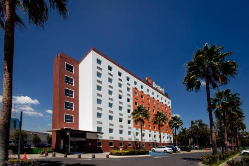 a large white building with palm trees in front of it at Hotel Hi! Zapopan in Guadalajara