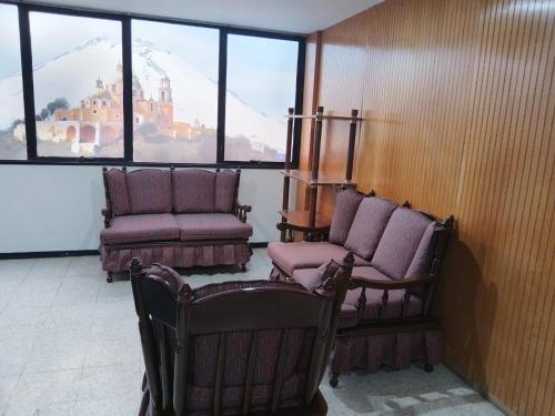 a room with two chairs and a couch and windows at Departamento 4 Ote in Puebla
