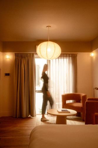 a woman walking through a living room with a window at Cholula Condesa Hotel by Lumina in Mexico City
