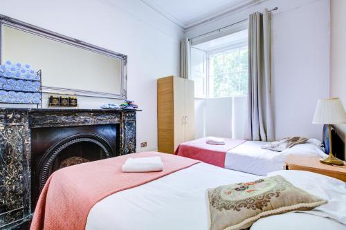 ロンドンにあるHyde Park 36 Hotelの暖炉と鏡付きの部屋のベッド2台