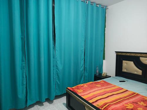 Un dormitorio con una cama y una cortina azul. en Modern Comfort Stay, en Sharjah