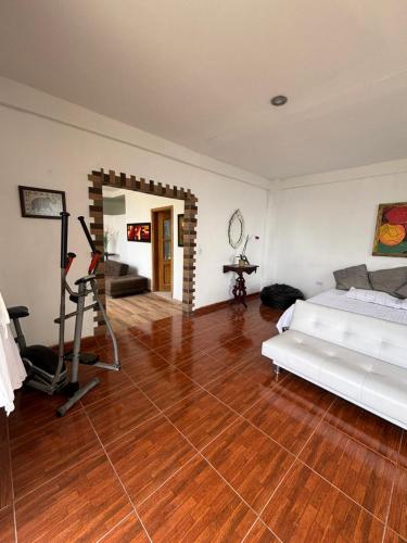 a living room with a white bed and a wooden floor at Hostal Santa Teresita in La Merced