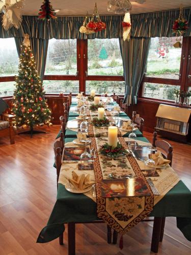 a long table in a room with a christmas tree at Achnabobane Farmhouse in Spean Bridge
