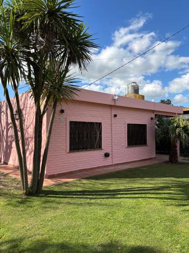 a pink building with a palm tree in a yard at Encantadora y espaciosa casa a dos cuadras de Laguna Chascomús in Chascomús