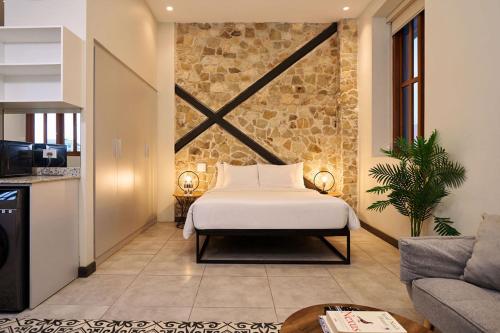 a bedroom with a bed and a stone wall at AmazINN Places Casa Fortaleza in Panama City